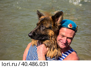 Moscow, Russia - August 02, 2017: Paratrooper in a blue beret closeup embraces a dog in a vest. Редакционное фото, фотограф Iva Noel / Фотобанк Лори