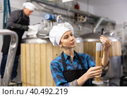 Woman brewer checks the amount of alcohol in beer using an alcoholmeter closeup. Стоковое фото, фотограф Яков Филимонов / Фотобанк Лори