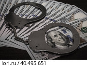 One hundred dollar bills and steel handcuffs close up. Стоковое фото, фотограф Артем Курутин / Фотобанк Лори
