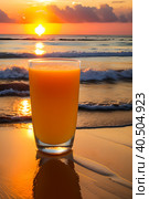 A glass of orange juice on the sea sand, small waves, romantic sunset. Стоковое AI-изображение, AI-художник Сергей Елизарьев / Фотобанк Лори