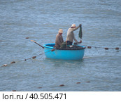 Two fishermen sail in a traditional Vietnamese boat. One of them throws the net. (2015 год). Редакционное фото, фотограф Ирина Кононова / Фотобанк Лори