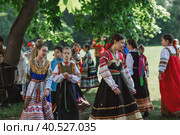 Russian folk traditions. Folk festivals. Children in beautiful Russian traditional outfits sing songs, dance and lead a round dance in Tsaritsyno Park. National Russian clothes. Sundresses and kokoshniks. (2023 год). Редакционное фото, фотограф Photojuli / Фотобанк Лори