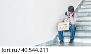 Need a job, asian unemployed adult male sitting on the stairs with poster. Стоковое фото, фотограф Ирина Кононова / Фотобанк Лори