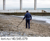 Поиск с помощью металлоискателя на зимнем пляже после шторма. Сочи (2023 год). Редакционное фото, фотограф Вячеслав Палес / Фотобанк Лори