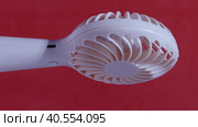 Portable fan on a stand. Revolves on a rotating electrical showcase. On a coral background. Close-up. Стоковое видео, видеограф Vadzim Yakubovich / Фотобанк Лори