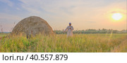 At sunset an senior Muslim man in an embroidered skullcap and white traditional Clothes mows hand-scythe grass in a hayfield. Стоковое фото, фотограф Ирина Кононова / Фотобанк Лори