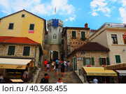 Herceg Novi, Montenegro, old town, Sat-kula tower, Sahat-kula, Tora, chapel tower or Clock tower 08.09.22 Tourists walk along the aisle under the city clock. Sunset, golden hour, summer evening. (2022 год). Редакционное фото, фотограф Юлия Петровская / Фотобанк Лори