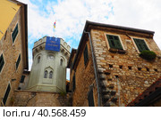 Herceg Novi, Montenegro, old town, Sat-kula tower, Sahat-kula, Tora, chapel tower or Clock tower 08.09.22 Tourists walk along the aisle under the city clock. Sunset, golden hour, summer evening. (2022 год). Редакционное фото, фотограф Юлия Петровская / Фотобанк Лори