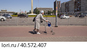 Пожилая женщина передвигается по улице с помощью ходунков. Липецк. (2023 год). Стоковое фото, фотограф Евгений Будюкин / Фотобанк Лори