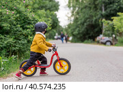 A cheerful little boy rides a running bike in a helmet outdoors. A happy child is engaged in an active sport. Protection. Life insurance and child safety. Стоковое фото, фотограф Photojuli / Фотобанк Лори