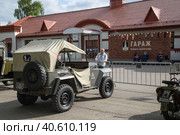 Мужчина фотографирует артиллерийский тягач ГАЗ-67Б (1944г., СССР), стоящий на открытой площадке перед зданием Музея Гаража особого назначения на ВДНХ в Москве (2023 год). Редакционное фото, фотограф Наталья Николаева / Фотобанк Лори