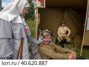Солдаты русской армии общаются с сестрами мелосердия времен Первой мировой войны в полевом госпитале на фестивале "Времена и эпохи" в парке города Москвы, Россия (2023 год). Редакционное фото, фотограф Николай Винокуров / Фотобанк Лори