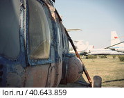 Бок старого ржавого вертолета на фоне стоящих пассажирских самолетов. The side of an old rusty helicopter against the background of a lighted field with abandoned passenger aircraft. Стоковое фото, фотограф Валерий Елистратов / Фотобанк Лори