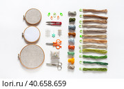 Materials for hand embroidery cross stitch and satin stitch: wooden hoops with canvas, set of special needles, needle threader, scissors and skeins of colorful cotton threads Mouline on white background. Стоковое фото, фотограф Виктория Катьянова / Фотобанк Лори