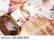 Пачка рублевых пятитысячных купюр лежит в старом кошельке на фоне денежных купюр. Стоковое фото, фотограф Николай Винокуров / Фотобанк Лори