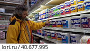Buyer selects paint and plaster in the store (2018 год). Редакционное фото, фотограф Анна Кривицкая / Фотобанк Лори