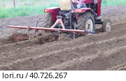 Harrow cultivator is attached from minitractor for plowing potato field in farm. Стоковое видео, видеограф Владимир Григорьев / Фотобанк Лори