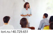 Positive male tutor giving lecture as part of educational program while standing in front of group of men in study hall. Стоковое видео, видеограф Яков Филимонов / Фотобанк Лори