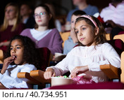 Preteen girl with african american friend watching movie in cinema. Стоковое фото, фотограф Яков Филимонов / Фотобанк Лори