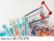 Toy shopping cart with Russian rubles money. Living wage and purchasing power concept. Стоковое фото, фотограф Сергей Толмачёв / Фотобанк Лори