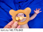 a baby on a blue background with a wooden rattle. Стоковое фото, фотограф Anastasia Kayander / Фотобанк Лори
