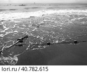 Buoys on a rope near sea water. The lifebuoys restraints to alert people to the depth of the water. Delimiting a place on a sandy beach between hotels. Wave with bubbles. Black white photo monochrome. Стоковое фото, фотограф Юлия Петровская / Фотобанк Лори