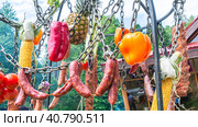 Овощи и мясные продукты готовятся на костре. Колбаса и свежие овощи подвешены на цепочке над грилем. Еда на открытом воздухе. Пикник в выходные. Стоковое фото, фотограф Эдуард Белкин / Фотобанк Лори