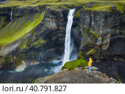 Man in yellow coat admire Haifoss Waterfall in Landmannalaugar canyon, Iceland. Aerial panoramic drone view (2020 год). Стоковое фото, фотограф Igor Tichonow / Фотобанк Лори