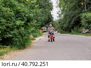 A cheerful little boy rides a running bike in a helmet outdoors. A happy child is engaged in an active sport. Protection. Life insurance and child safety. Стоковое фото, фотограф Photojuli / Фотобанк Лори