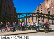 HAMBURG, GERMANY - May 5, 2018: Bicycling tour in old Speicherstadt near Wandrahmsfleet house in Hamburg. Стоковое фото, фотограф Igor Tichonow / Фотобанк Лори