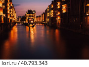 The Warehouse District - Speicherstadt in twilight. Tourism landmark of Hamburg. View of Wandrahmsfleet in light of lantern lamp. Port of Hamburg within the HafenCity quarter (2018 год). Стоковое фото, фотограф Igor Tichonow / Фотобанк Лори
