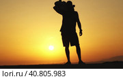 Silhouette of a man standing on sunset and with a longboard on his shoulder. Стоковое видео, видеограф Константин Шишкин / Фотобанк Лори
