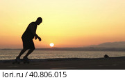 Silhouette of a man skating on a longboard at sunset by the ocean. Стоковое видео, видеограф Константин Шишкин / Фотобанк Лори