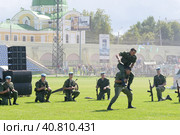 Во время празднования дня ВДВ на стадионе двое десантников демонстрируют навыки рукопашного боя с ножом и против ножа. Другие спецназовцы с автоматами в руках наблюдают за поединком. Сзади, через задымление, видны зрители со знамёнами и часть православного Храма. (2015 год). Редакционное фото, фотограф Сергей Никифоров-Гордеев / Фотобанк Лори