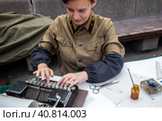 Женщина в советской форме железнодорожника печатает документ на пишущей машинке на Чистопрудном бульваре в центре города Москвы, Россия (2023 год). Редакционное фото, фотограф Николай Винокуров / Фотобанк Лори
