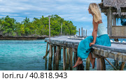 Girl Sitting on Wooden Pier of an Homestay looking into blue ocean, Bamboo Hut in background, Gam Island, West Papuan, Raja Ampat, Indonesia (2016 год). Стоковое фото, фотограф Igor Tichonow / Фотобанк Лори