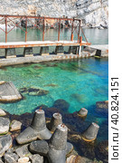 Tetrapods and an old rusty pier in clear turquoise sea water. In the background is a steep cliff. A beautiful tranquil seascape. Стоковое фото, фотограф Воловодов Владимир / Фотобанк Лори