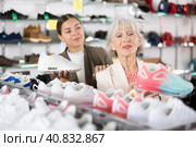 Elderly mom strongly recommends her doughter to pay attention to classic model of light sneakers. Стоковое фото, фотограф Яков Филимонов / Фотобанк Лори
