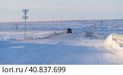 The car drives along a snow-covered road in the tundra in the Arctic. Transport infrastructure in the Far North. Cold winter weather. The nature of the polar region. Traveling by car to the Arctic. Стоковое фото, фотограф Андрей Степанов / Фотобанк Лори