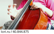 Picicato on the cello. A child girl in a pink jacket plays pizzicato with her fingers the cello without a bow. An entry-level violoncello study at a music school. Стоковое видео, видеограф Юлия Петровская / Фотобанк Лори