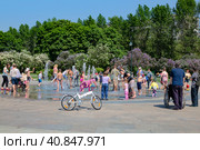 Взрослые и дети освежаются в фонтанах в жаркий летний день. Сиреневый сад, Москва, Россия (2015 год). Редакционное фото, фотограф Наталья Волкова / Фотобанк Лори