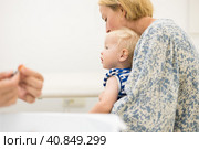 Child beeing vaccinated by pediatrician in presence of his mother. Preventive vaccination against Diphtheria, whooping cough, tetanus, hepatitis, haemophilus influenzae, pneumococcus, poliomyelitis. Стоковое фото, фотограф Matej Kastelic / Фотобанк Лори