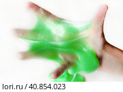 Hand Playing with textured slime with bubbles, stretching the gooey substance. Female teen hand holding green shining slime, squeezing it. Adorable Girl stretching slime toy to the sides. Liquid toy. Стоковое фото, фотограф Марина Демидюк / Фотобанк Лори