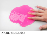 Playing with textured slime with bubbles, stretching the gooey substance. Female teen hand holding pink shining slime, squeezing it. Adorable Girl stretching slime toy to the sides. Liquid toy. Стоковое фото, фотограф Марина Демидюк / Фотобанк Лори