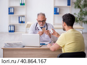 Young male patient visiting old male doctor. Стоковое фото, фотограф Elnur / Фотобанк Лори