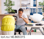 Young male employee looking after newborn at workplace. Стоковое фото, фотограф Elnur / Фотобанк Лори