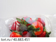 Ripe strawberries in a plastic package on a white background. Delicious fresh berries in a container for sale to customers. Keeping food fresh. Healthy food, vitamins and microelements. Стоковое фото, фотограф Юлия Петровская / Фотобанк Лори