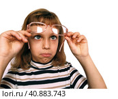 Cute 7 year old Caucasian girl looks into glasses. Eyes in a bunch. Ophthalmic problems in children. Myopia, exophoria and astigmatism. Selection of glasses. Isolate white background. Back to school. Стоковое фото, фотограф Юлия Петровская / Фотобанк Лори