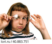 Cute 7 year old Caucasian girl looks into glasses. Eyes in a bunch. Ophthalmic problems in children. Myopia, exophoria and astigmatism. Selection of glasses. Isolate white background. Back to school. Стоковое фото, фотограф Юлия Петровская / Фотобанк Лори