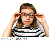 Cute 7 year old Caucasian girl looks into glasses. Eyes in a bunch. Ophthalmic problems in children. Myopia, exophoria and astigmatism. Selection of glasses. Isolate white background. Back to school. Стоковое фото, фотограф Юлия Петровская / Фотобанк Лори